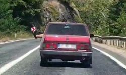Ayaklarını camdan sarkıtarak trafiği tehlikeye attı